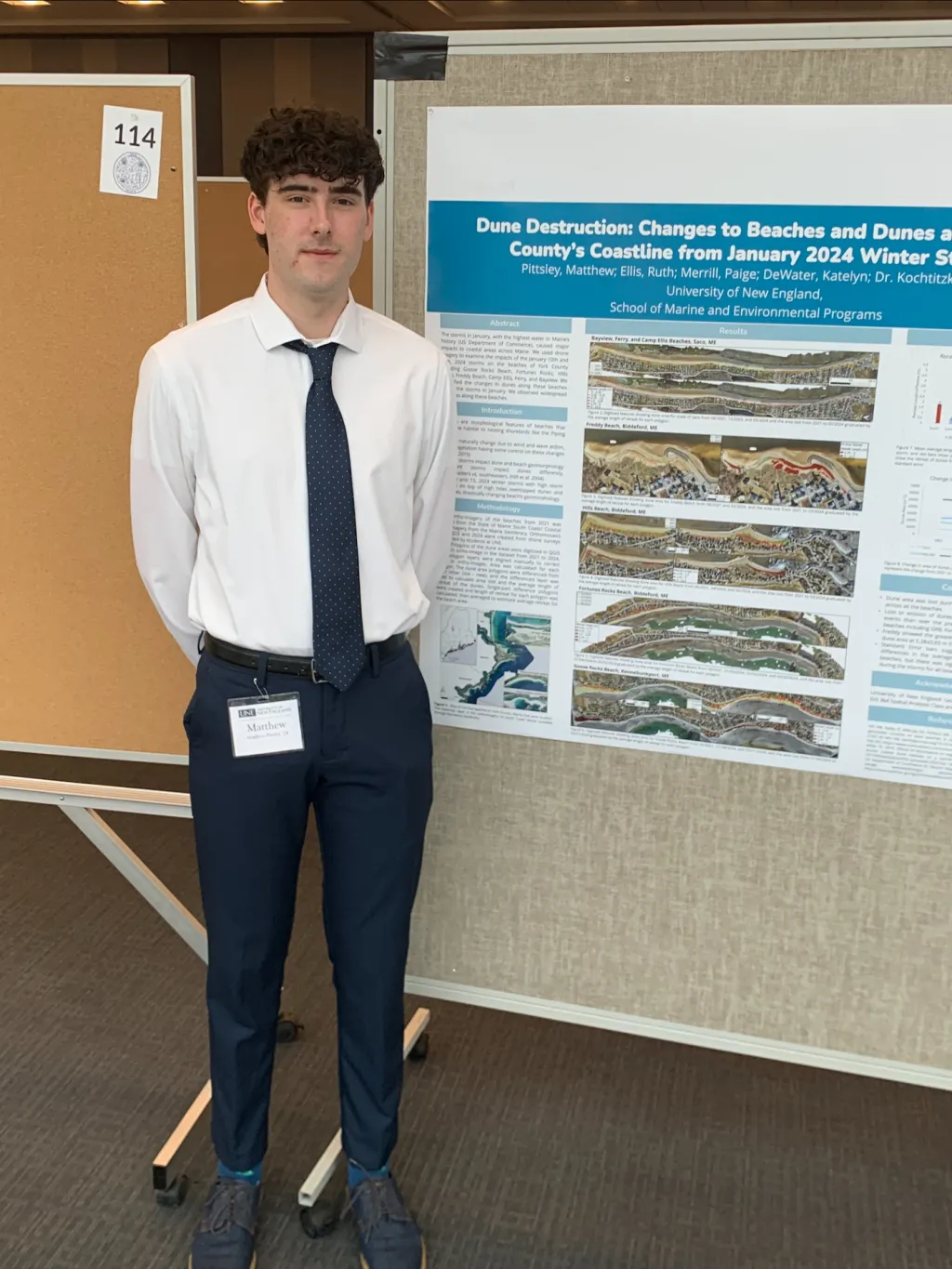 A UNE student (Matthew Pittsley) poses in front of a research poster