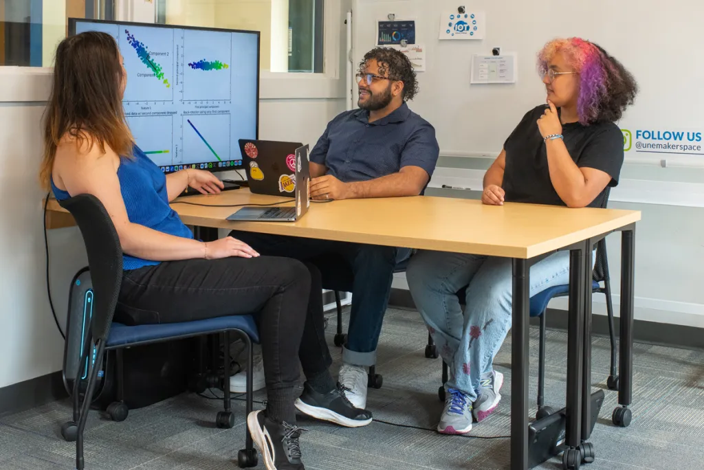 A group of students look at a graph of data on a large monitor