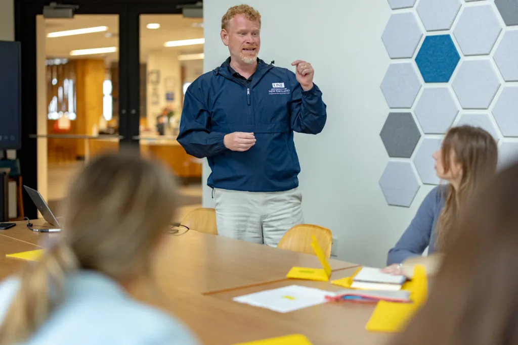 Jeremy Pare speaks to three students sitting at a large table