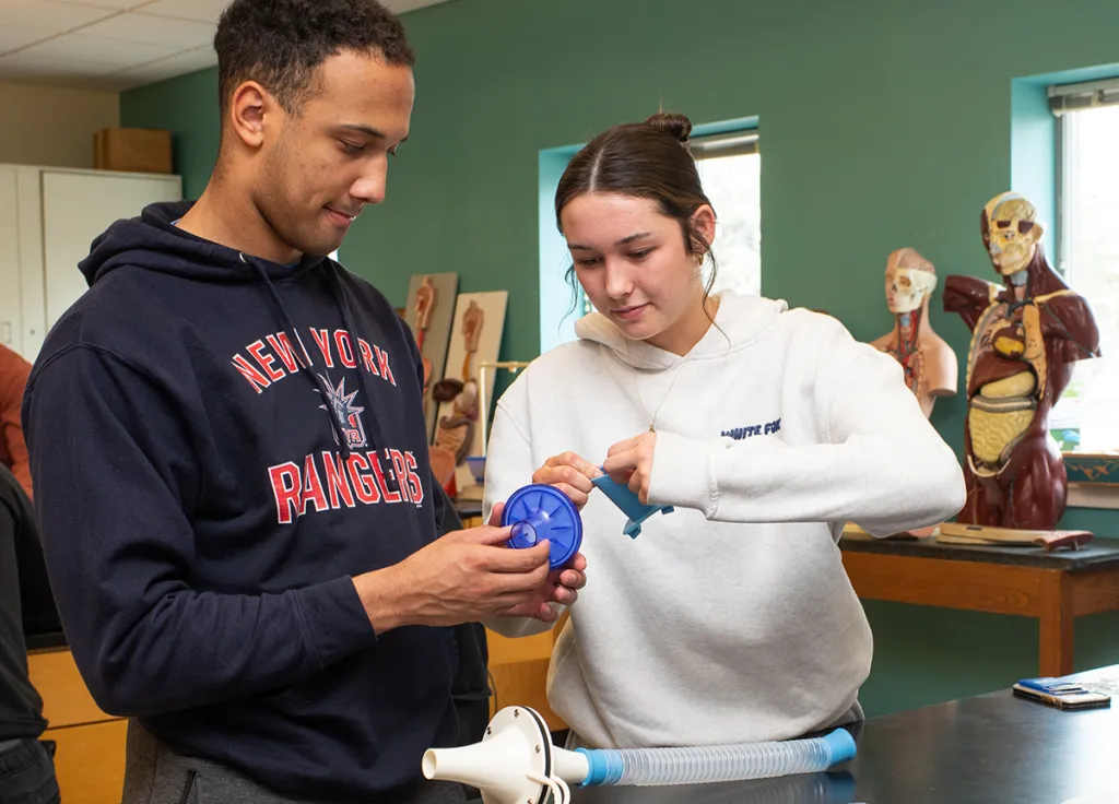 Two U N E students prepare a respiratory kit for class