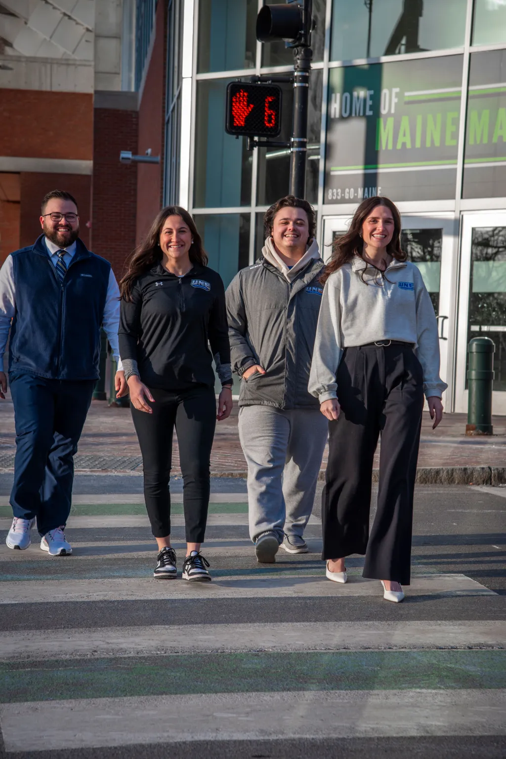 UNE students cross the street in front of the Cross Insurance Arena