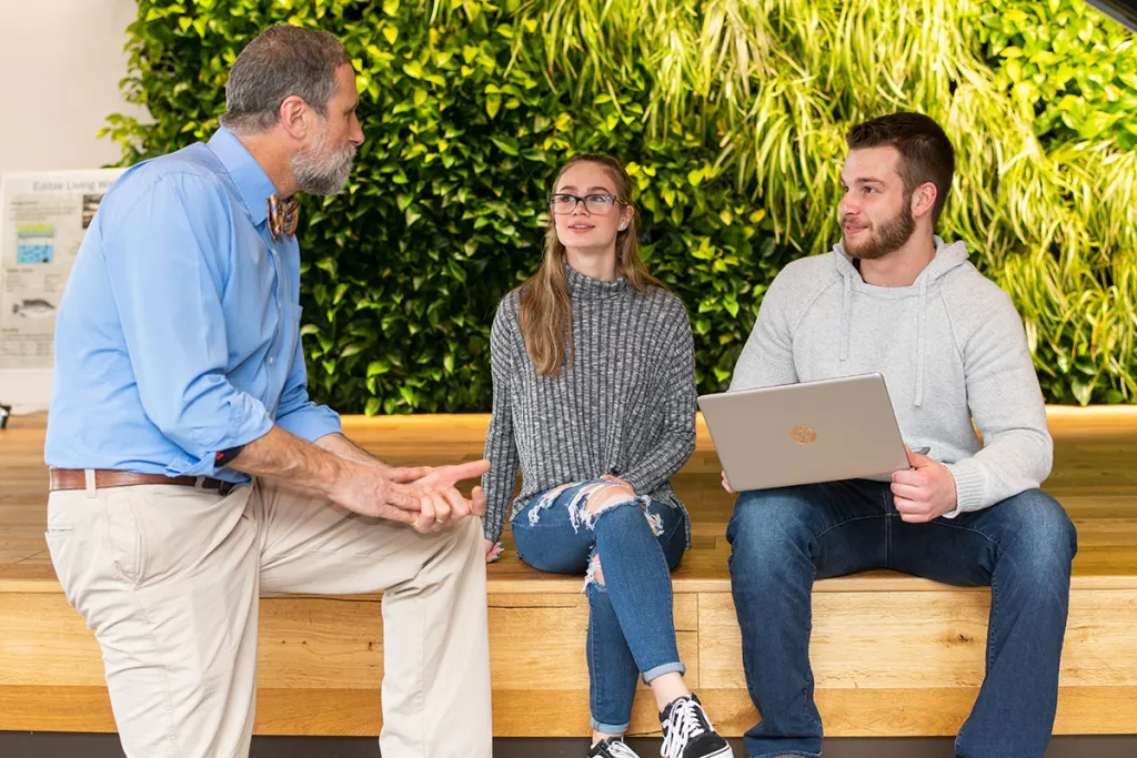 A U N E professors works with two U N E liberal arts students