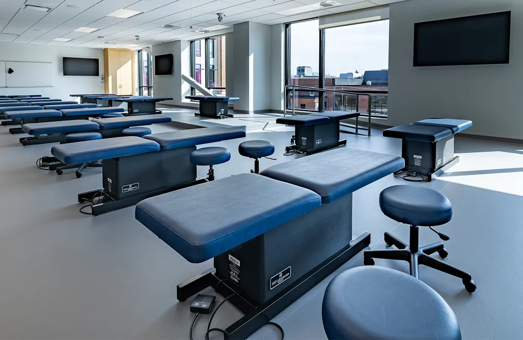 A classroom with several rows of new treatment tables and rolling stools