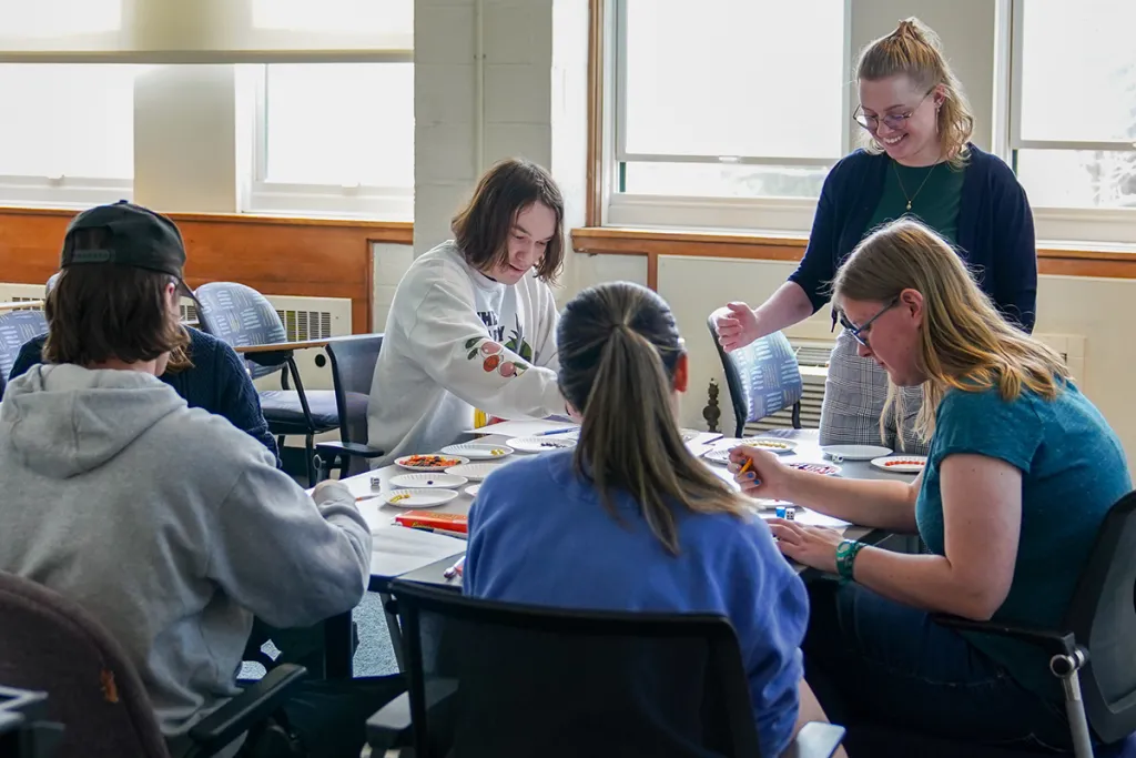 A professor and their group of students sit around a table while using Reese's Pieces candy to test the rate of incidence of a fake population