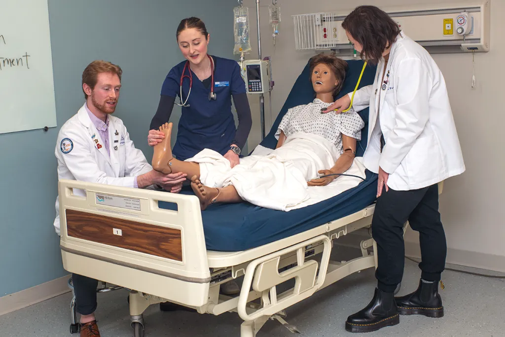 Various health students work together to treat a patient simulator in the Sim Lab