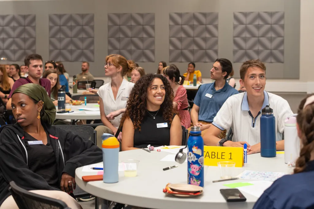U N E students wearing sit around a table labeled during the annual Clarion competition.
