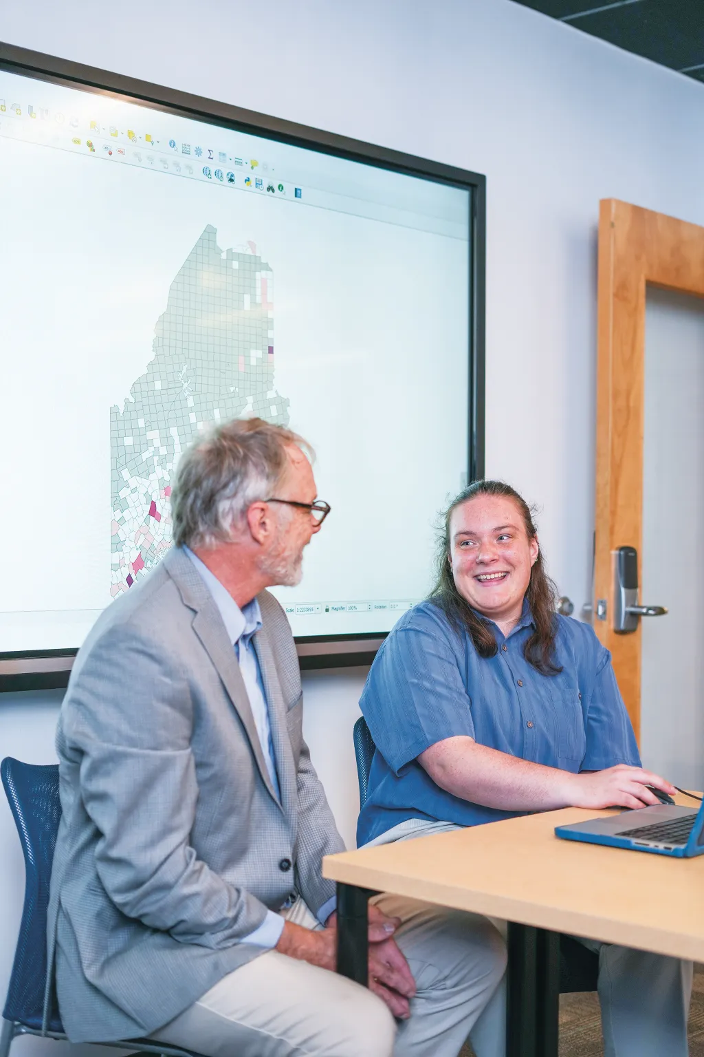 Ruth Ellis (Environmental Science, ’25) and Cameron Wake, Ph.D. review a map of Maine displaying environmental and demographic data on a computer screen.