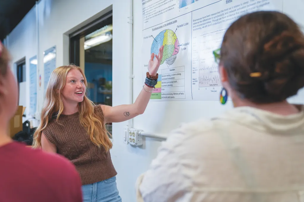 Jessica Howard presents information about brain anatomy and function on a whiteboard to Milo Lypps and Sophia Crockett-Current.