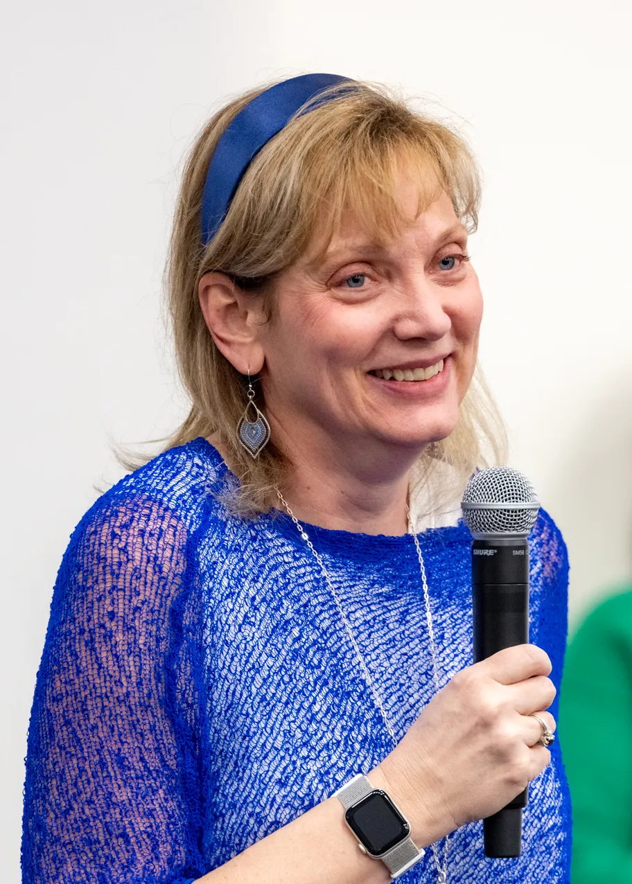 UNE First Lady Lynn Brandsma, Ph.D., speaks into a microphone