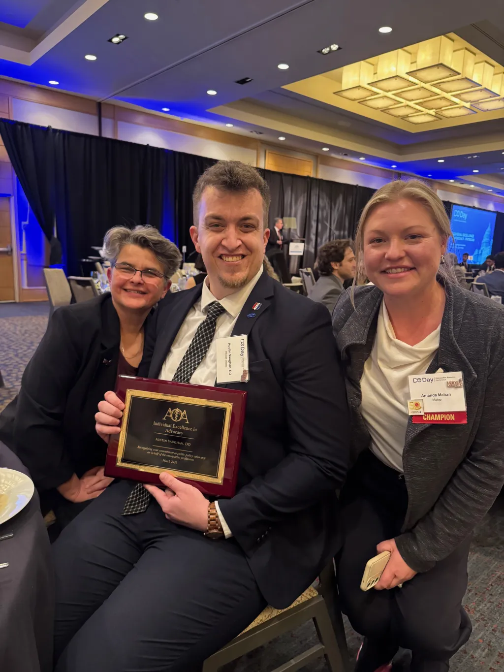 UNE COM alum Austin Vaughan, D.O. ’25 poses with an award with mentors