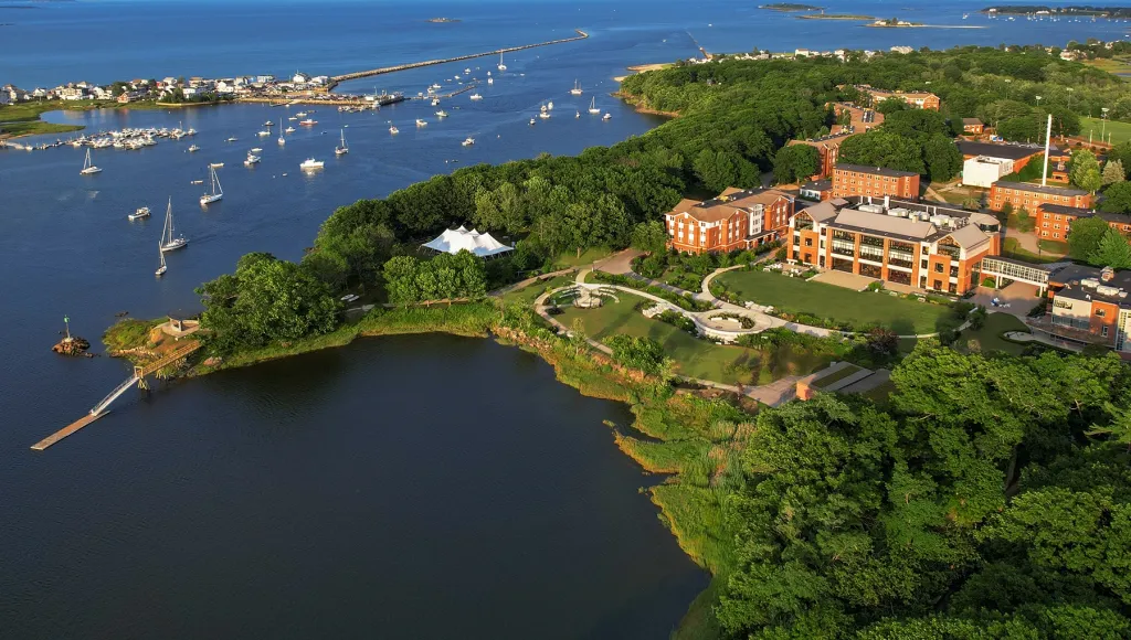 A bird's-eye view of the scenic waterfront Biddeford Campus with landscaped grounds and a boat-filled harbor.