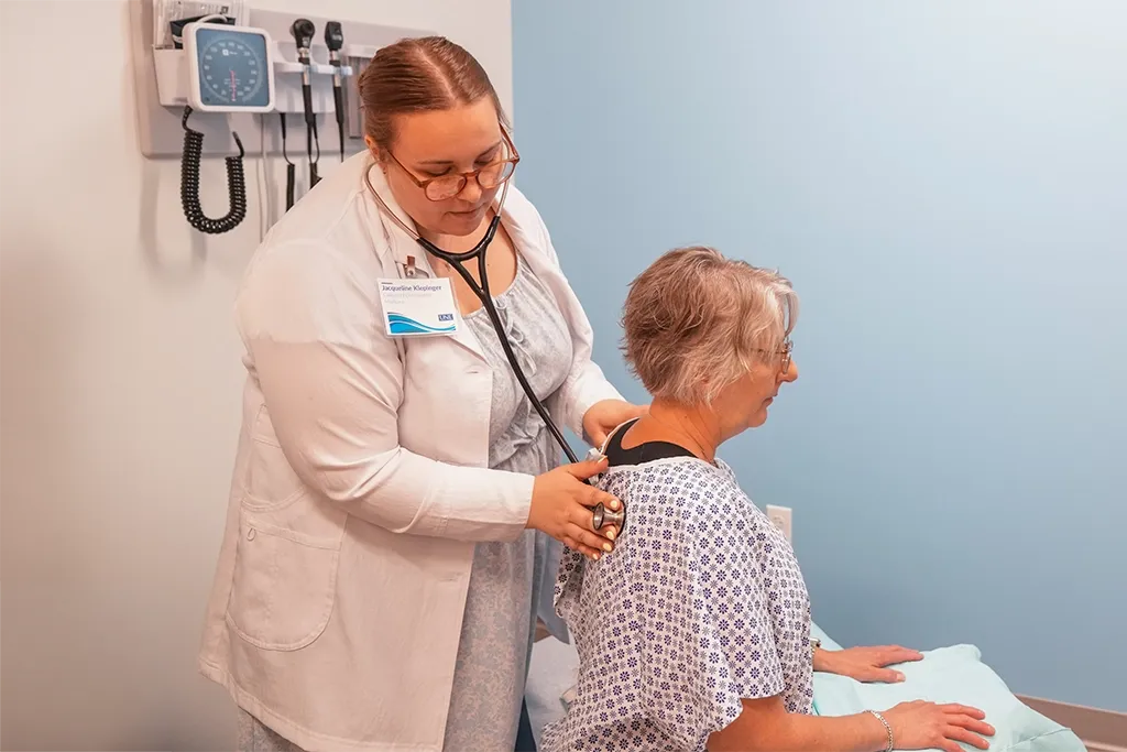 A U N E College of Osteopathic Medicine student uses a stethoscope to examine a patient during a clinical exam.