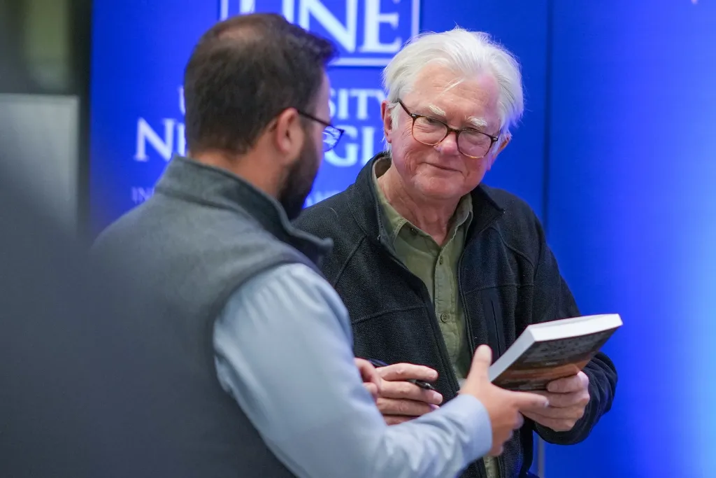 Author David Shaw signs a book for an attendee at a U N E Spark Conversation event.