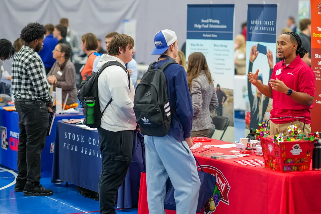 U N E students talk with an employer representative at a booth during Industry Exploration Day.