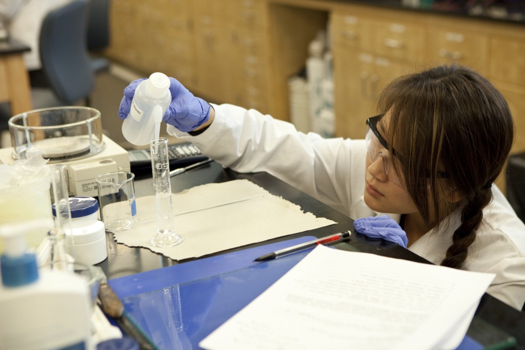 A female student fills test tubes in a research lab