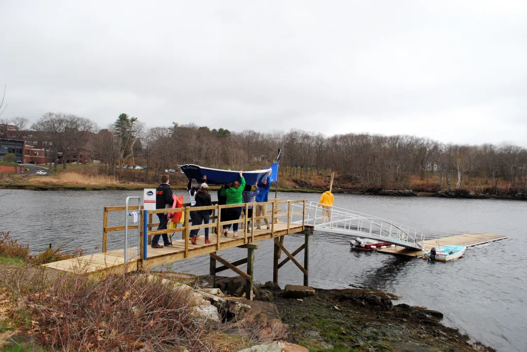 Members of the Boatbuilding class carry Sea Basket down the Biddeford Campus pier.