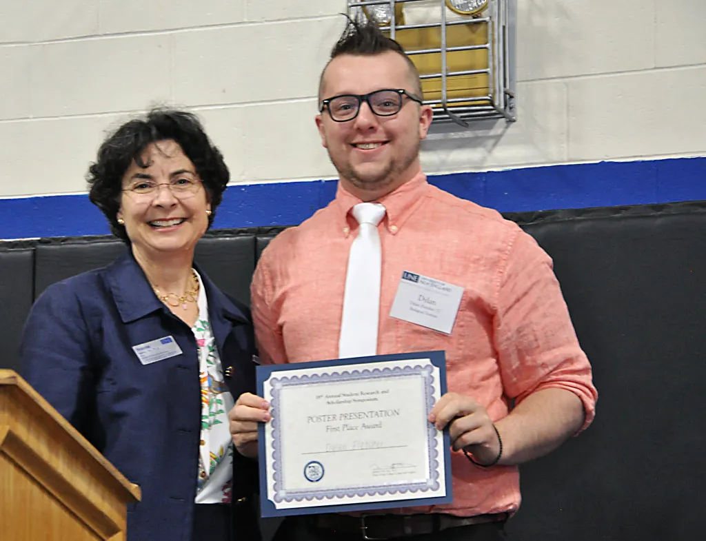 Dylan Fletcher receives his award for first place in the Poster Presentation category from Jeanne Hey, Ph.D., dean of the Colleg