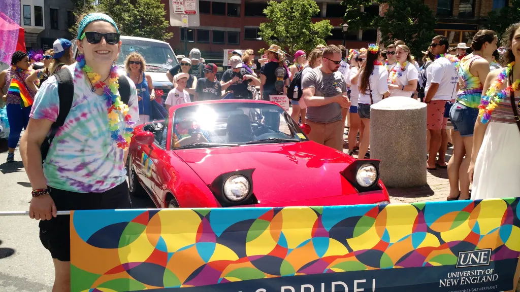 A UNE-branded convertible leads the way as the crowd cheers.
