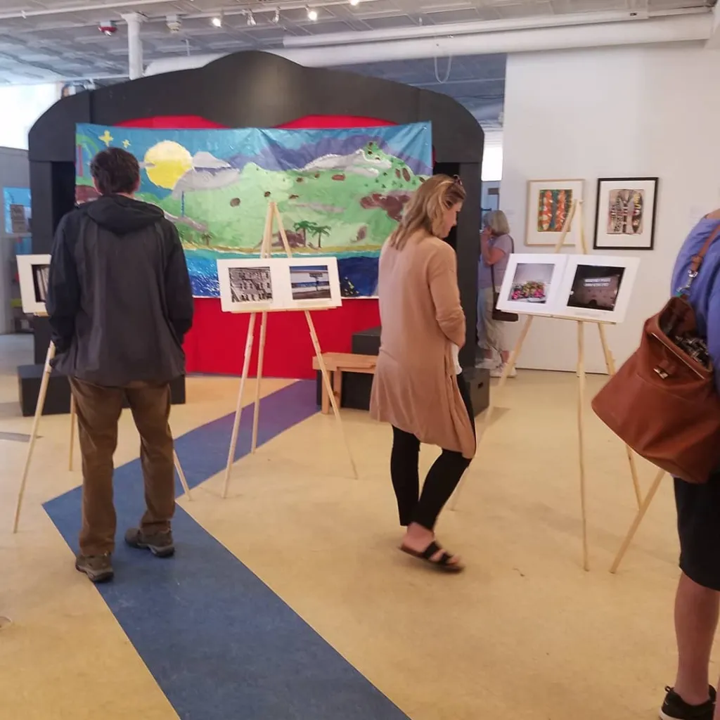 Visitors to Engine look over photos that represent how high school students view their community