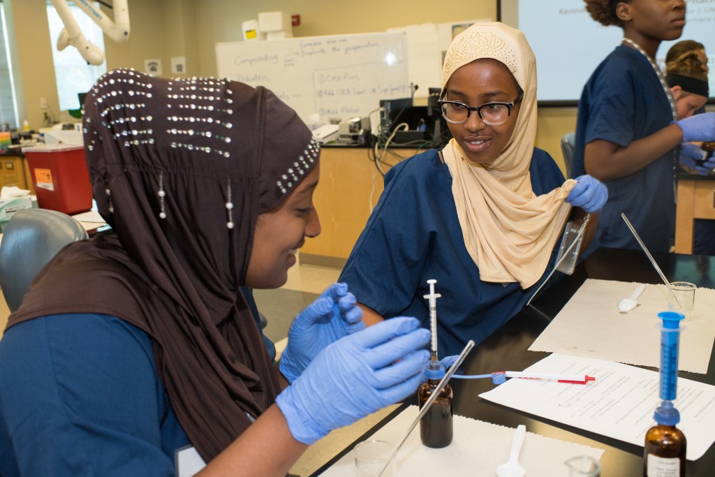 Deering High School students Fahima Hassan and Hanan Omar learn to make a pediatric medication