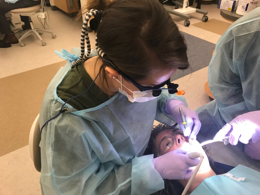 UNE dental student Stephanie Beeckel performs a cleaning on patient Mary Rena