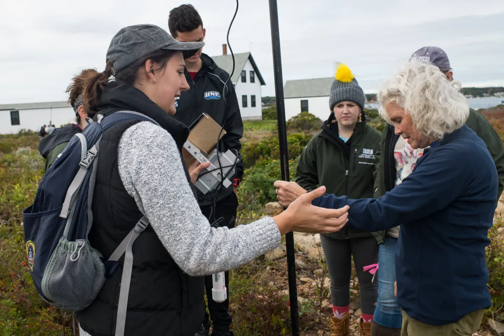 Instructor Pam Morgan and students install a monitor to collect wind data