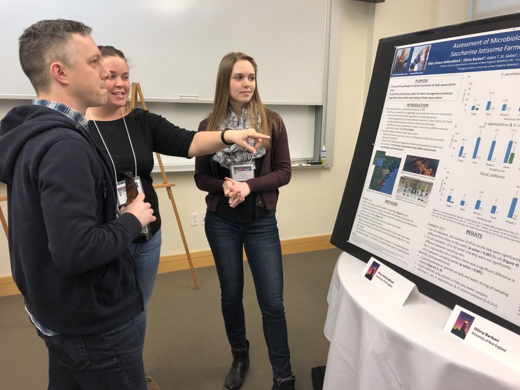 An attendee at the showcase (foreground) learns about research conducted by Mary Hollandbeck a Class of ’18 Marine Science major