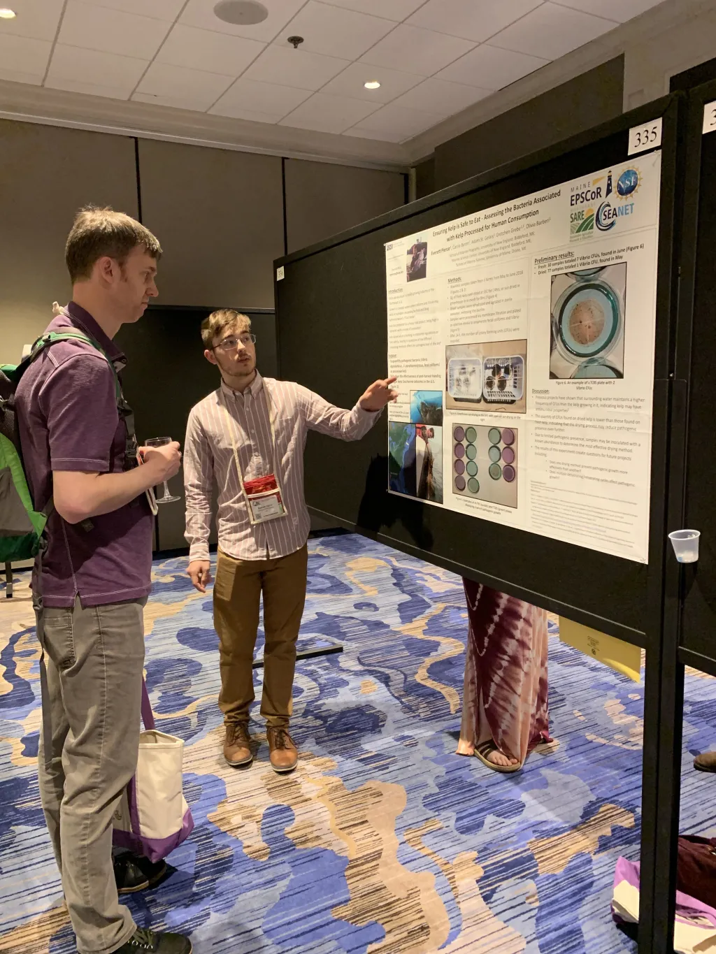 Everett Pierce discusses his poster with a conference attendee
