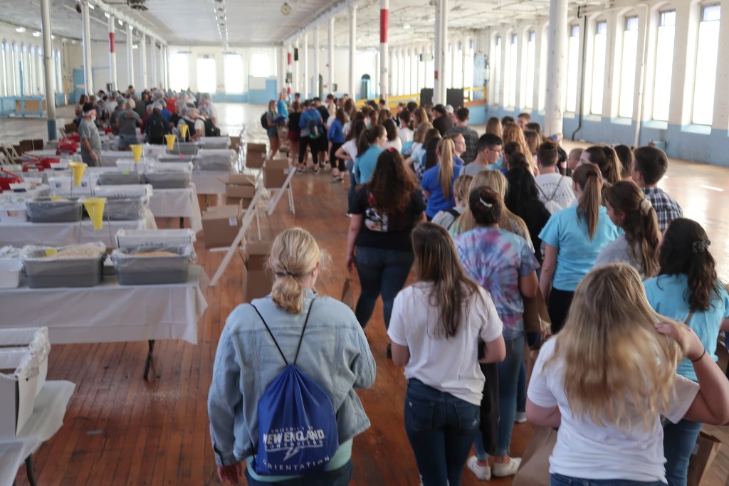 Students line up inside the Pepperell Mill to package meals