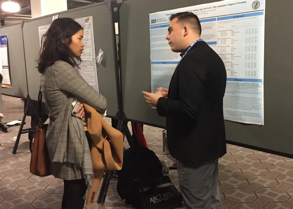 UNE alumnus Ben Katz speaks with a meeting attendee