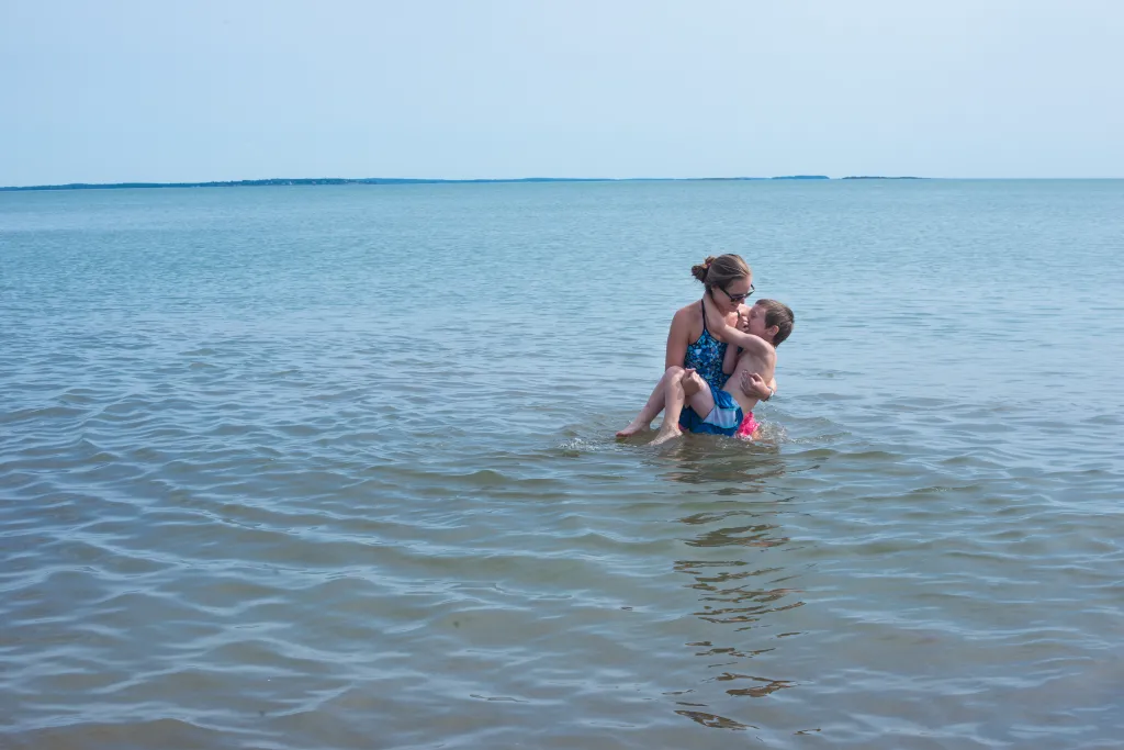 UNE student and camp counselor Meaghan Bessette plays with camper Kaiden Huot during a field trip to the beach.
