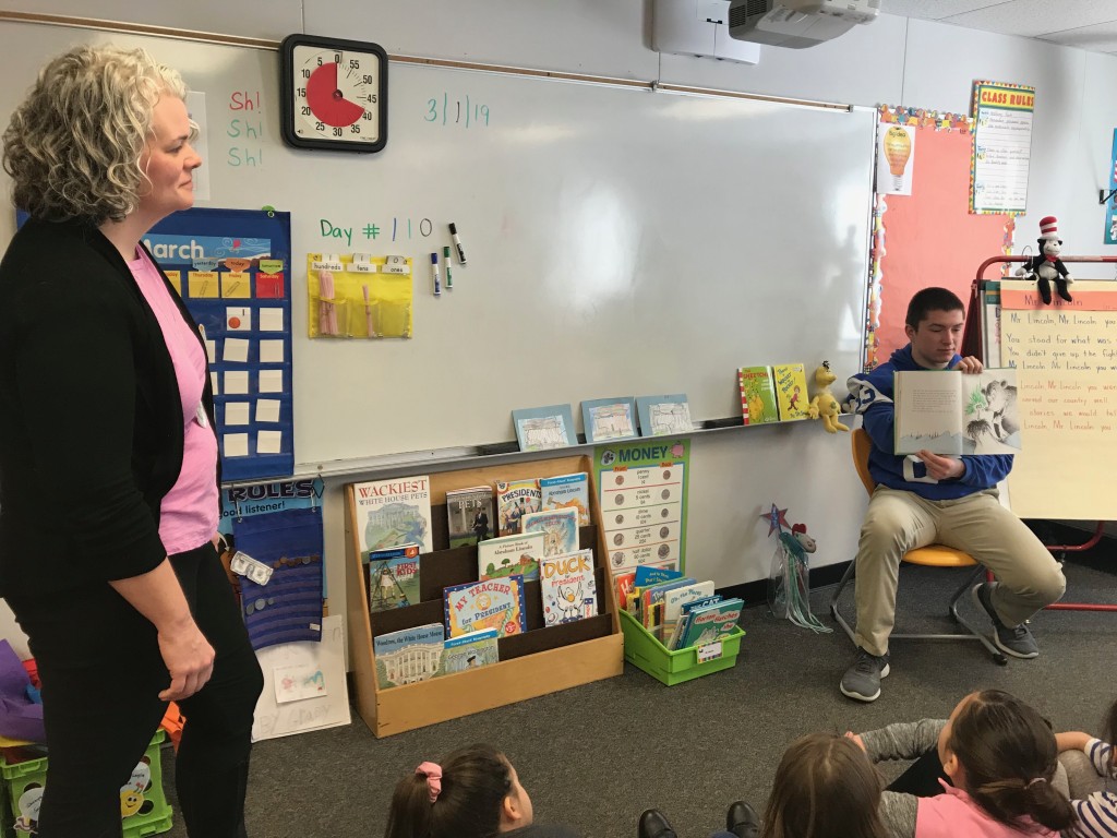 Audrey Bartholomew, chair of the Education Department, visits a classroom while football player Trevor Therrien is reading