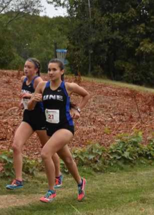 UNE Women's cross country team members run on the grass