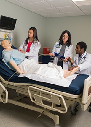 Health graduate students practicing on a dummy in the Simulation Lab