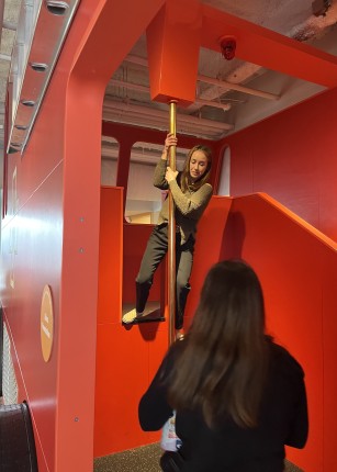 A student slides down the pole of an imitation firetruck