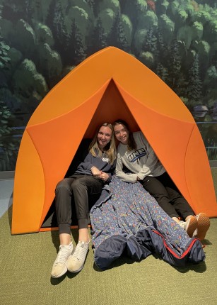 Two female students pose inside a tent