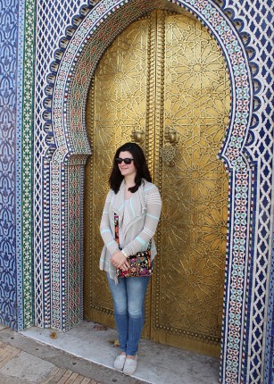 A student standing in front of a gilded door in Morocco
