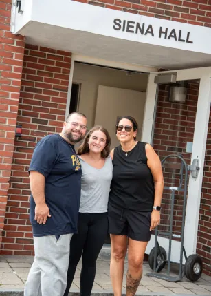 A student and her family pose in front of Siena Hall