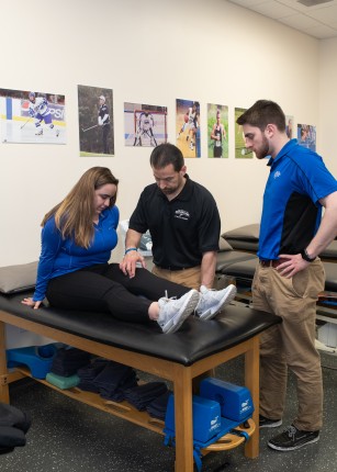 A professor and two students talking in the athletic training lab
