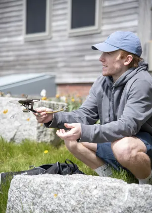A male student demonstrates how to use a flint to light a fire