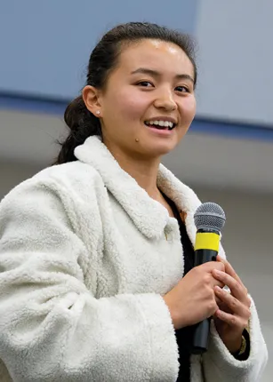 A student speaks into a microphone at a President's Forum