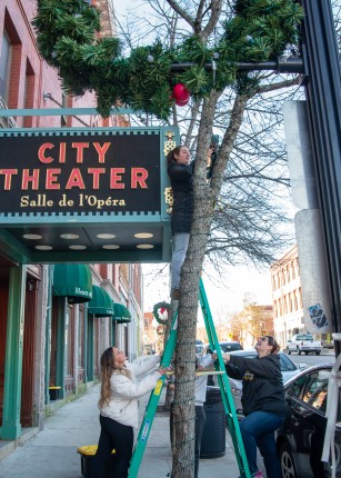 Students hang lights on a tree in front of Biddeford City Theater