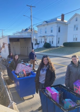 Students and volunteers load toys and gifts into a box truck