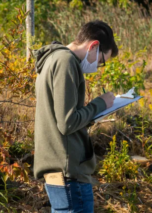 A student writes notes on a clipboard
