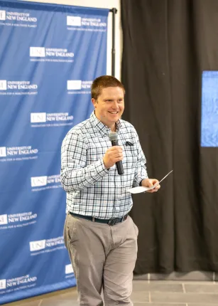 Professor Will Kochtitzky speaks into a microphone