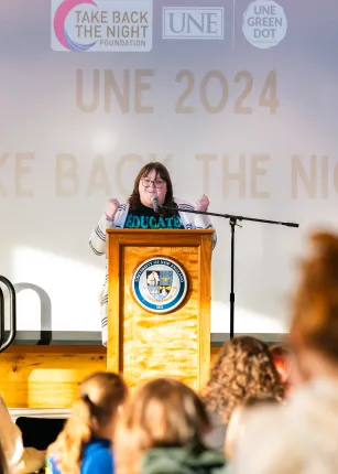 A woman speaks at a podium to a crowd