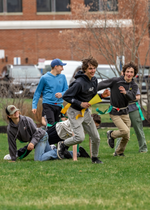 A group of teens plays field games on the campus lawn
