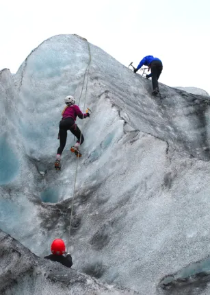 Three U N E students climb the side of a glacier