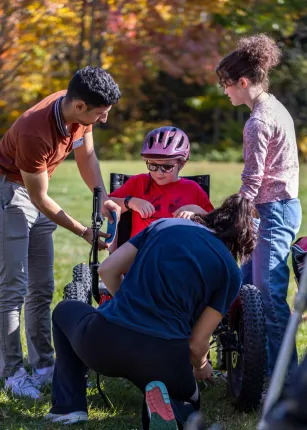UNE volunteers assist a power soccer player outside