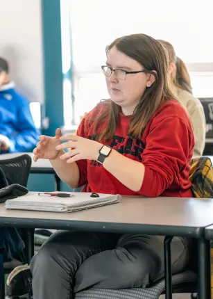 A UNE student asks a question during class